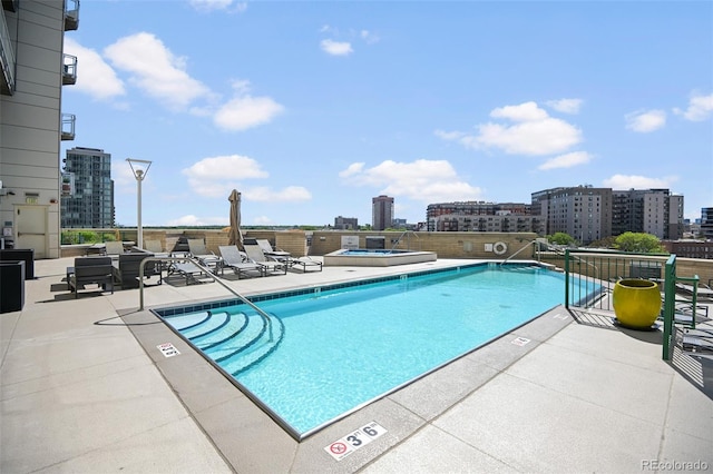 community pool featuring a view of city, a patio, and a hot tub