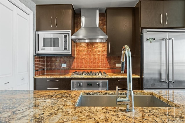 2001 Lincoln St Unit 2420, Denver, CO 80202 - kitchen with wall chimney exhaust hood, built in appliances, light stone counters, tasteful backsplash, and a sink