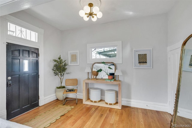 foyer with a wealth of natural light, baseboards, a chandelier, and wood finished floors