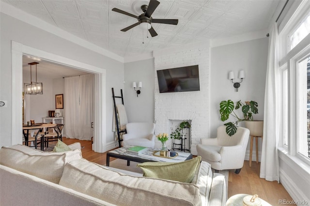 living area featuring an ornate ceiling, a wealth of natural light, a brick fireplace, and wood finished floors