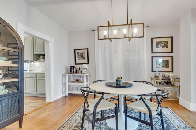 dining space featuring light wood finished floors, baseboards, and a notable chandelier