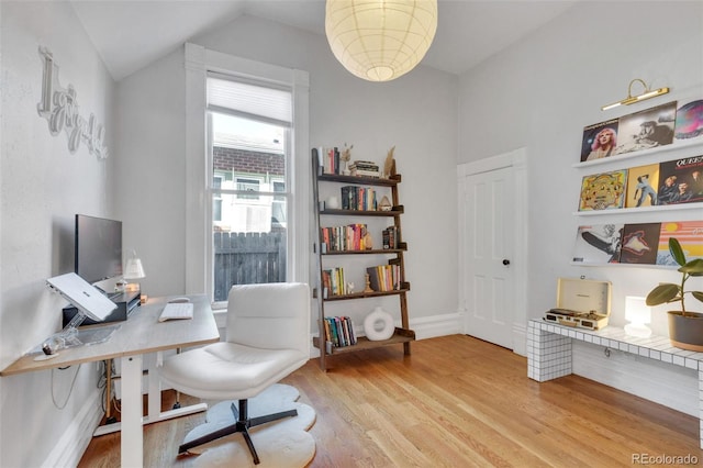 office area with light wood-type flooring, vaulted ceiling, and baseboards