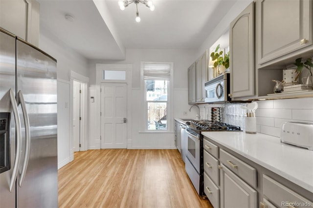 kitchen with light wood-style floors, gray cabinets, stainless steel appliances, and a sink