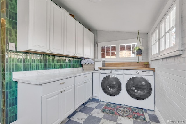 clothes washing area with cabinet space, washing machine and dryer, and light floors