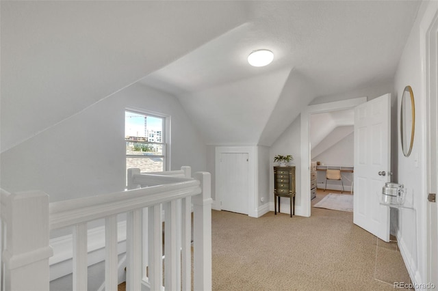 corridor featuring vaulted ceiling, carpet floors, and an upstairs landing