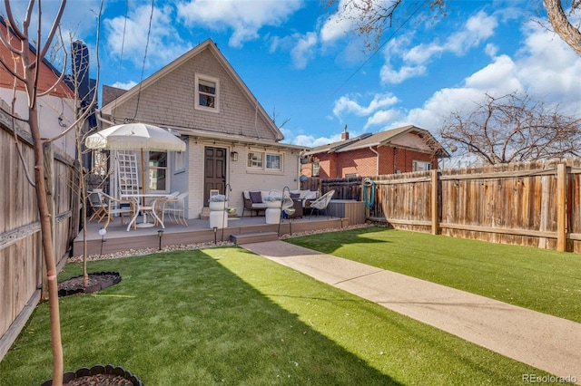 back of property featuring a deck, brick siding, a lawn, and a fenced backyard