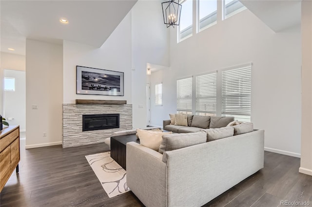 living room featuring an inviting chandelier, a wealth of natural light, a fireplace, and dark hardwood / wood-style flooring