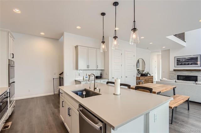 kitchen featuring a center island with sink, white cabinetry, sink, and dark wood-type flooring