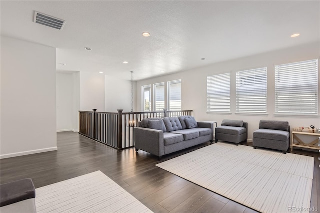 living room featuring a textured ceiling, a chandelier, and dark wood-type flooring