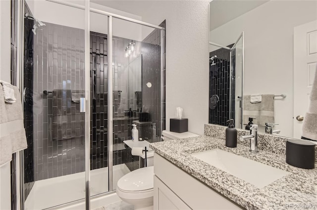 bathroom featuring a shower with door, vanity, and toilet