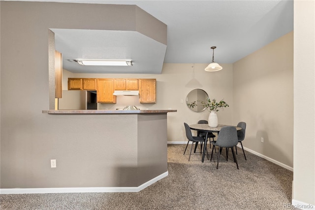kitchen with under cabinet range hood, freestanding refrigerator, carpet, and baseboards