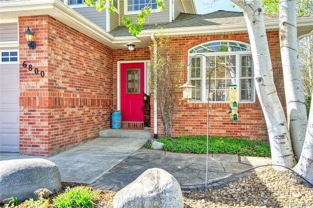property entrance featuring brick siding and a shingled roof