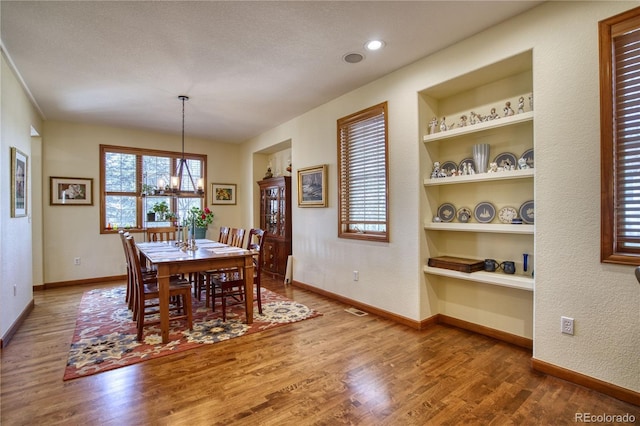 dining area featuring wood finished floors, baseboards, and an inviting chandelier