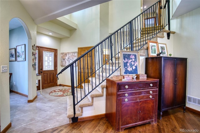 entryway with arched walkways, baseboards, stairs, and visible vents