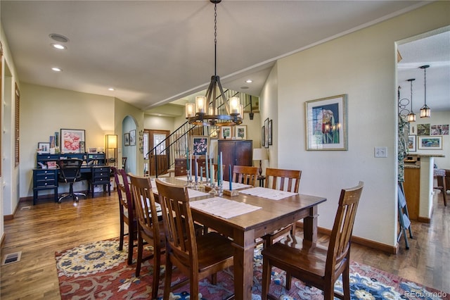 dining area with baseboards, a notable chandelier, wood finished floors, and visible vents