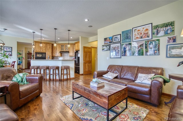 living room featuring recessed lighting, wood finished floors, and a textured ceiling