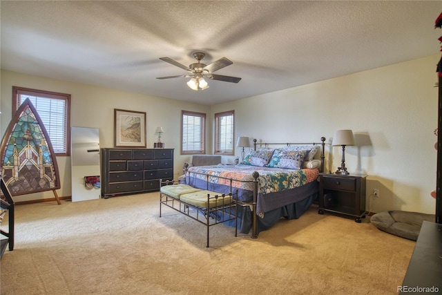 bedroom with ceiling fan, carpet floors, and a textured ceiling