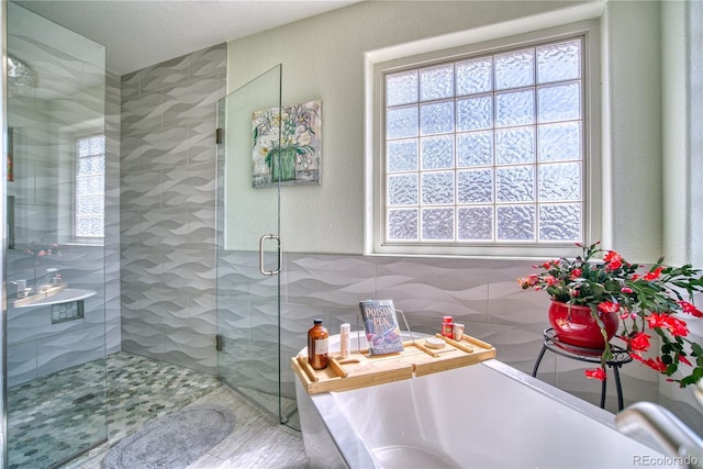 bathroom featuring a shower stall, a freestanding tub, and tile walls