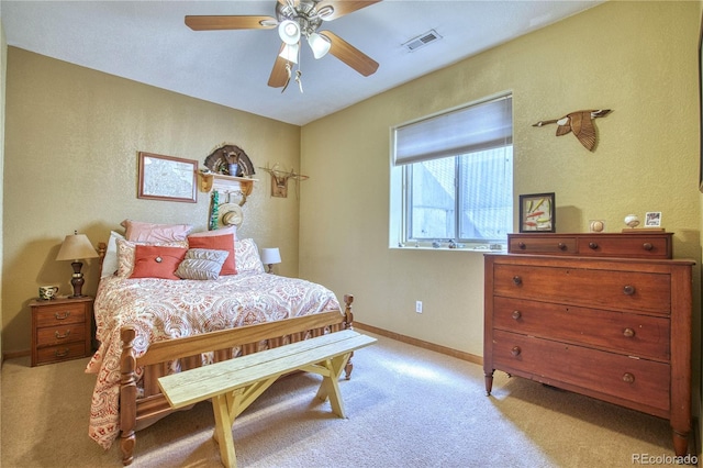 bedroom with ceiling fan, light carpet, a textured wall, and visible vents