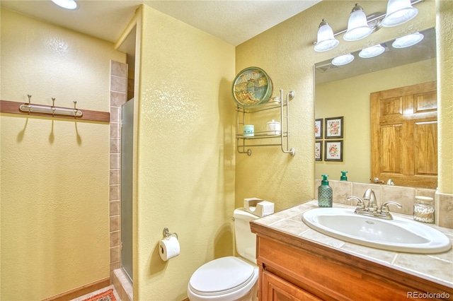 full bath with toilet, a textured wall, vanity, and a shower