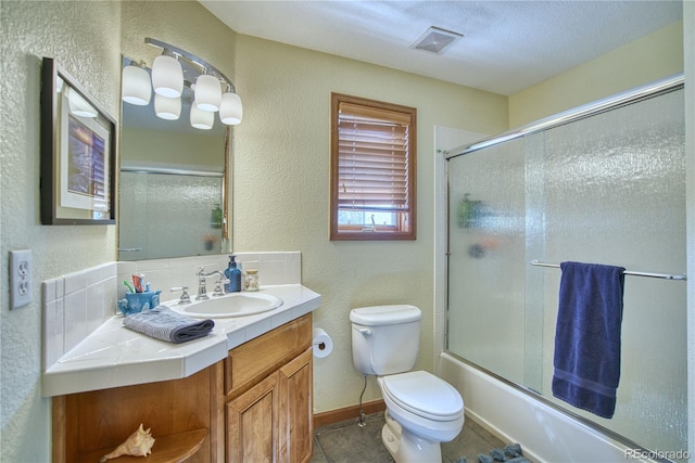 bathroom with a textured wall, visible vents, toilet, and vanity
