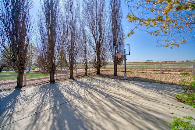 view of basketball court with fence and basketball hoop