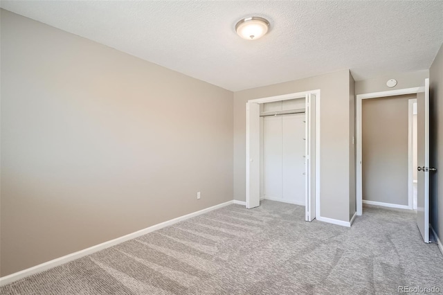 unfurnished bedroom with light colored carpet, a closet, and a textured ceiling