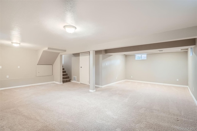 basement featuring light colored carpet and a textured ceiling