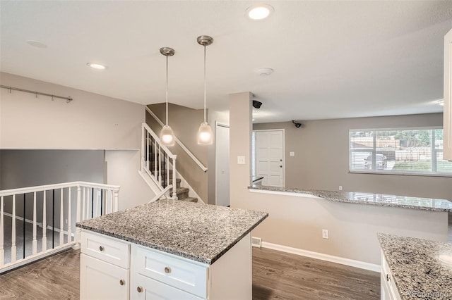 kitchen featuring dark hardwood / wood-style flooring, pendant lighting, white cabinets, and light stone counters