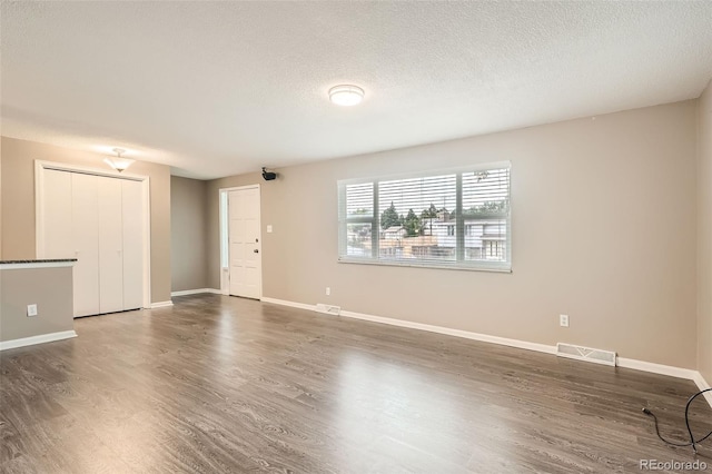 empty room with a textured ceiling and dark hardwood / wood-style flooring