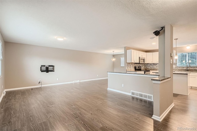 kitchen with pendant lighting, dark hardwood / wood-style flooring, white cabinets, and appliances with stainless steel finishes