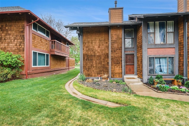 back of property featuring a chimney and a yard