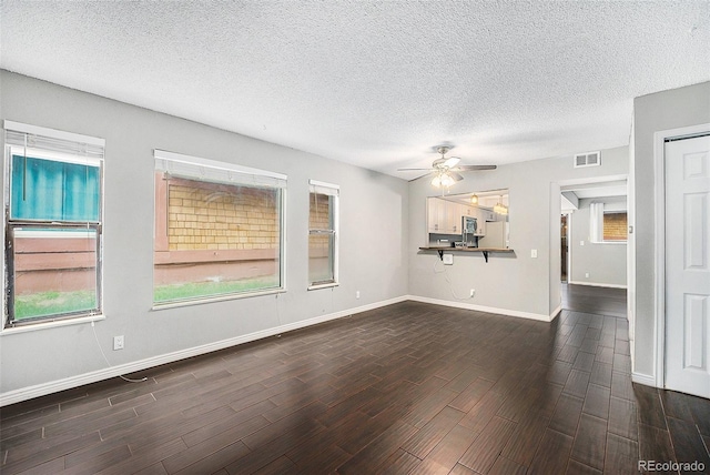 unfurnished living room with dark wood-type flooring, ceiling fan, a textured ceiling, and baseboards
