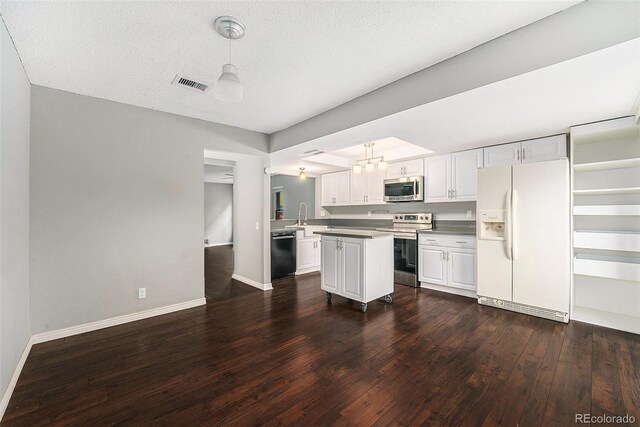kitchen with appliances with stainless steel finishes, dark wood finished floors, baseboards, white cabinetry, and pendant lighting