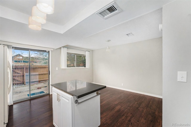 kitchen with dark countertops, dark wood finished floors, white cabinets, freestanding refrigerator, and baseboards
