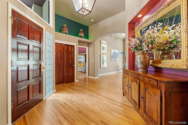 474 Silbrico Way, Castle Rock, CO 80108 - foyer entrance with arched walkways, light wood-type flooring, a towering ceiling, a chandelier, and baseboards