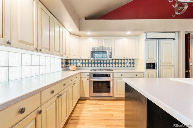 474 Silbrico Way, Castle Rock, CO 80108 - kitchen with stainless steel appliances, vaulted ceiling, light countertops, light wood-style flooring, and backsplash