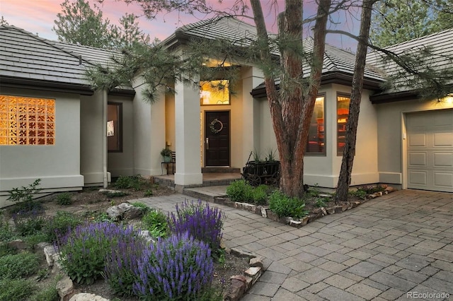 474 Silbrico Way, Castle Rock, CO 80108 - exterior entry at dusk featuring stucco siding, an attached garage, and driveway
