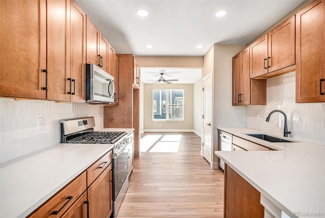 kitchen featuring sink, appliances with stainless steel finishes, tasteful backsplash, ceiling fan, and light wood-type flooring