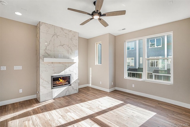 unfurnished living room featuring light wood-type flooring, ceiling fan, and a premium fireplace