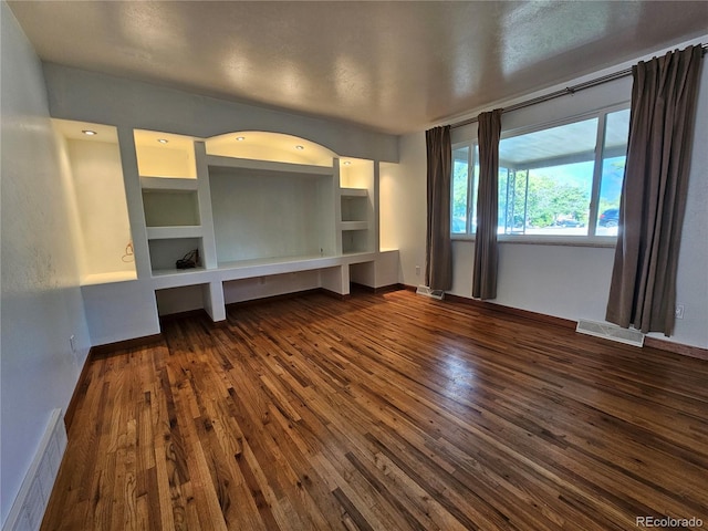 unfurnished living room featuring dark hardwood / wood-style flooring and built in shelves