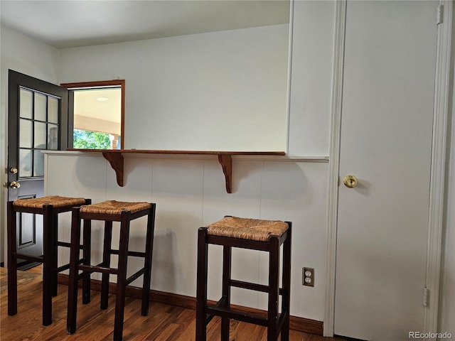 interior space featuring dark wood-type flooring and a kitchen breakfast bar