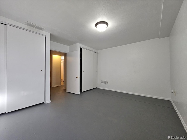 unfurnished bedroom featuring multiple closets and a textured ceiling