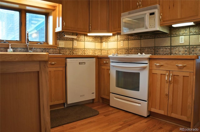 kitchen with light hardwood / wood-style flooring, white appliances, and tasteful backsplash