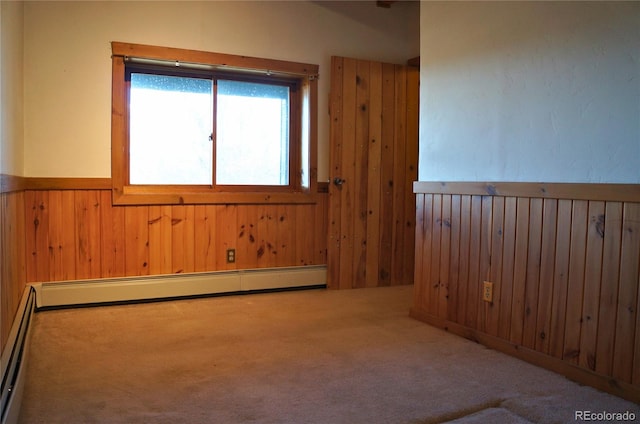 spare room featuring baseboard heating, wooden walls, and carpet