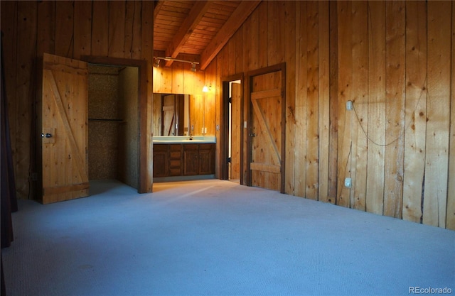 carpeted empty room with vaulted ceiling with beams, wood ceiling, and wood walls