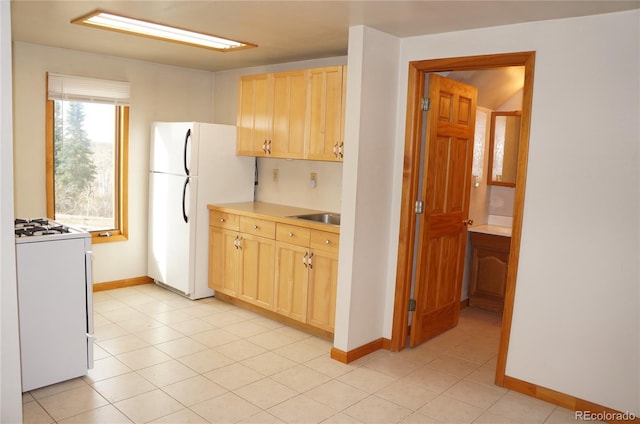 kitchen featuring light brown cabinetry, light tile patterned floors, sink, and white appliances