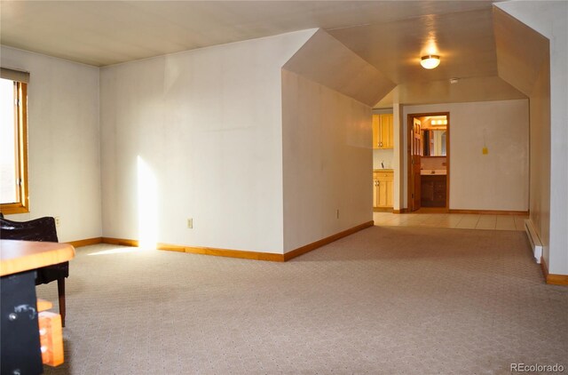 carpeted empty room featuring vaulted ceiling and a baseboard heating unit