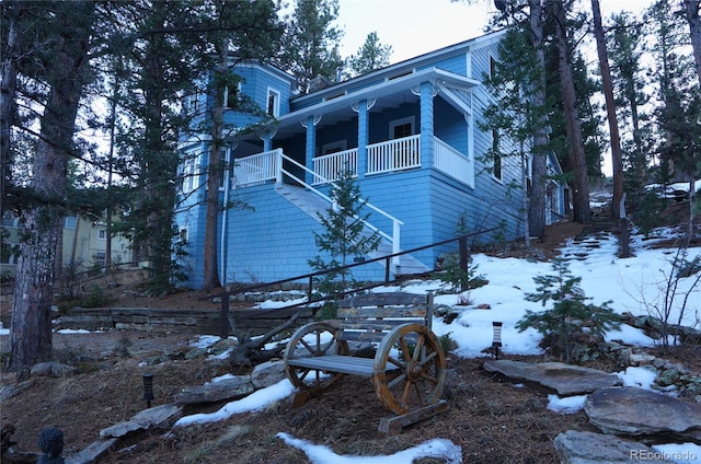 view of snow covered exterior with a porch and stairs