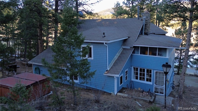 rear view of property featuring roof with shingles